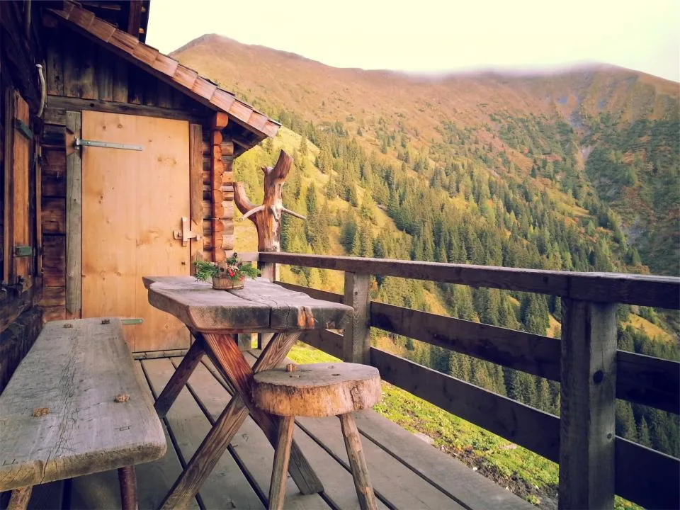Wooden deck with a table and railing overlooking hills
