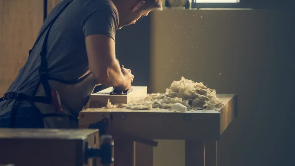 Carpenter planing a board at a workbench
